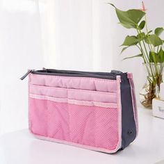 a pink purse sitting on top of a white table next to a potted plant