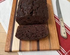 a loaf of chocolate cake sitting on top of a wooden cutting board