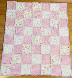 a pink and white patchwork quilt on a wooden floor