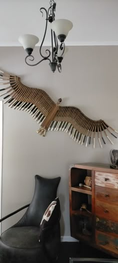 a large bird sculpture hanging from the ceiling above a chair in a room with two lamps