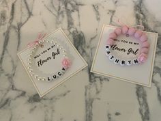 two pink bracelets with flowers on them sitting next to each other in front of a card