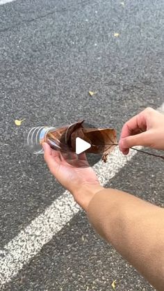 a person holding an empty glass bottle in their hand on the side of the road