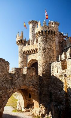 the entrance to an old castle with flags flying on it's roof and walls