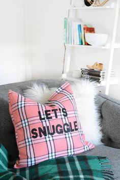 a plaid pillow that says let's snuggle on it, sitting on a couch