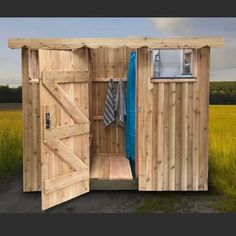 a wooden shed with an open door and towel hanging on it's side in a grassy field