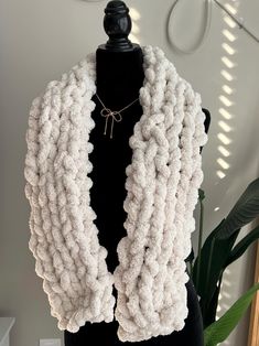 a white knitted scarf sitting on top of a mannequin