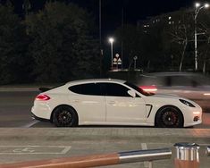 a white car is parked on the side of the road at night with other cars in the background