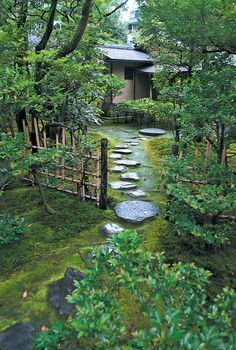 a garden with stepping stones in the grass and trees around it, leading to a small building