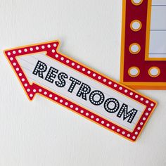 a red and white arrow with the word restroom painted on it next to a sign that says restroom