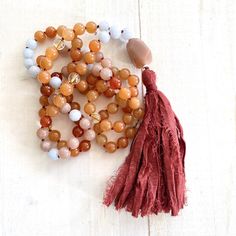 "A wonderful Mala for helping with insecurities. Handcrafted with Aquamarine for support when feeling overwhelmed and Peach Aventurine for assistance when making decisions. This Mala also consists of Sunstone which is known as a stone of leadership and personal power along with Carnelian to calm temper and give a sense of humor. An accent stone of Citrine is worked in for joy and happiness. All these healing stones are hand knotted into this beautiful 108 bead Mala. Charm not included, please se Carnelian Beaded Bracelets With Natural Stones For Meditation, Spiritual Hand-strung Amber Beaded Necklaces, Spiritual Amber Beaded Necklaces With Natural Stones, Spiritual Amber Beaded Necklace With Natural Stones, Hand-strung Orange Beads As A Gift, Bohemian Orange Crystal Necklace With Natural Stones, Orange Bohemian Crystal Necklace With Natural Stones, Spiritual Aventurine Beaded Necklace As Gift, Handmade Spiritual Coral Beaded Necklaces