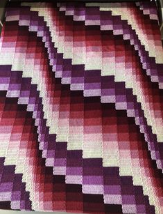 a crocheted blanket that has been made into a large pattern with purples and reds