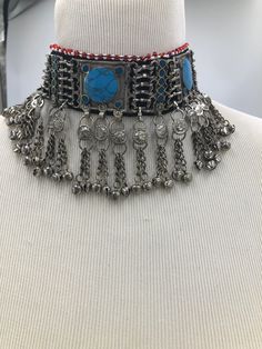 * This rusty silver choker necklace is a heavily embellished yet absolutely elegant piece of craft. The turquoise stones embedded within the necklace, along with the long dangling chain tassels, flaunting all the traditional vibes. This exclusive choker is handmade masterpiece, adorned with metallic weaving technique. You can pair this astonishing article with any trendy outfit, to add a pinch of ethnic touch to your fashion statement. Or compliment your traditional look by pairing it with your Turquoise Metal Necklace For Festivals, Traditional Turquoise Choker Jewelry, Bohemian Choker Necklace With Dangling Beads, Artisan Choker For Festivals, Handmade Turquoise Choker Necklace, Bohemian Turquoise Choker For Festivals, Handmade Turquoise Choker For Festivals, Silver Beaded Turquoise Necklace For Festivals, Artisan Handmade Silver Choker