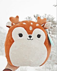 a person holding up a brown and white stuffed animal with antlers on it's head