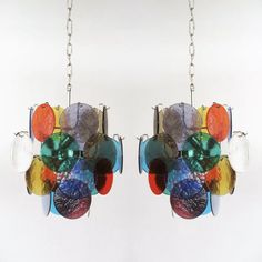 the multicolored glass chandelier is hanging from a metal chain with two hooks