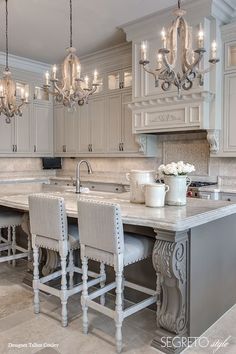 a large kitchen with white cabinets and chandeliers