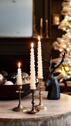 three candles sitting on top of a table next to a christmas tree