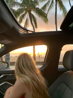 a woman sitting in the driver's seat of a car looking out at the ocean