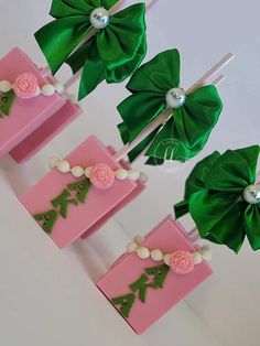 four pink and green candy bars with bows on them are sitting next to each other