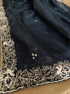 This is a fascinating pure organza silk saree in stunning black color, monochrome look. Saree features a dazzling beads and pearl work embroidery of floral design throughout the edges of the saree. Simple pearl work is twinkling all over the body of the saree. The beads and pearl embroidery are delicately hand embellished. Organza is a lightweight plain weave fabric. The pure organza attributes to a very comfy and flowy drape. Organza is considered as one of the most stylish and glamorous wear. Pearl Work Embroidery, Saree Simple, Pearl Work Saree, Cutdana Work, Pearl Work, Pearl Embroidery, Organza Silk Saree, Simple Pearl, Black Saree