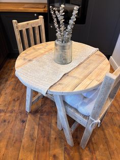 a wooden table with two chairs and a vase filled with flowers on top of it