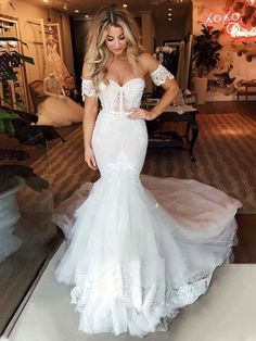 a woman in a white wedding dress posing for the camera with her hands on her hips