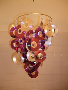 a chandelier made out of cds hanging from the ceiling in front of a tiled wall