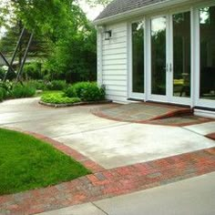 a white house with an open patio and sliding glass doors on the front door is surrounded by lush green grass