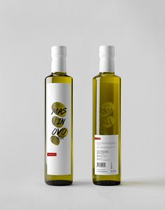 two bottles of olive oil sitting side by side next to each other on a white surface