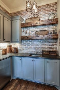 a kitchen with gray cabinets and brick wall