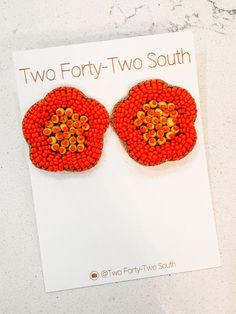 two forty - two south earrings with orange and yellow beads on white paper next to marble counter top