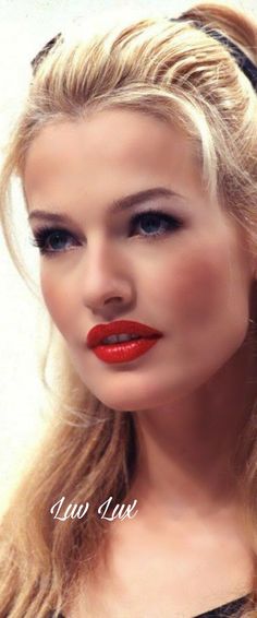 a woman with long blonde hair and red lipstick wearing a black headband, posing for the camera