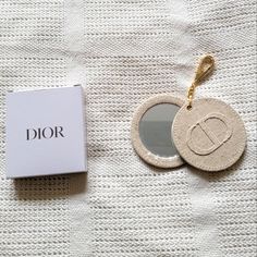 the dior key chain is next to an empty box on a white cloth surface