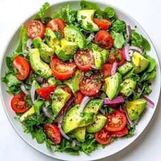 a salad with tomatoes, avocado, onions and lettuce on it