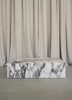 a marble bench sitting in front of curtains