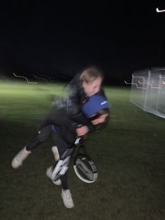 two young boys are playing with each other on a bike in the grass at night