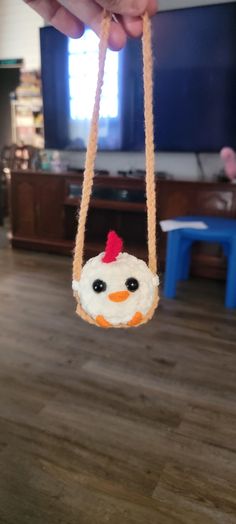 a person is holding a chicken ornament in front of a television set and table