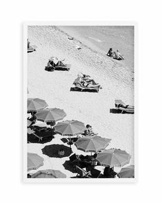 black and white photograph of people laying on the beach with umbrellas in front of them