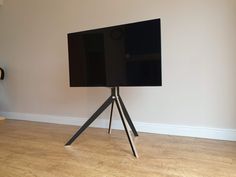 a flat screen tv sitting on top of a wooden tripod