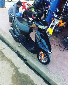 a man working on a motor scooter in the street