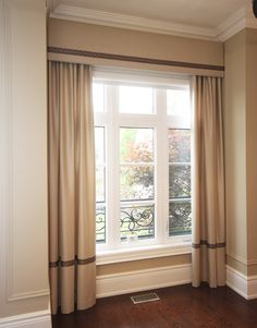 an empty room with wood floors and white curtains on the windowsill, along with a wooden floor