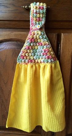 a yellow dress hanging on the side of a wooden cabinet with buttons and crochet