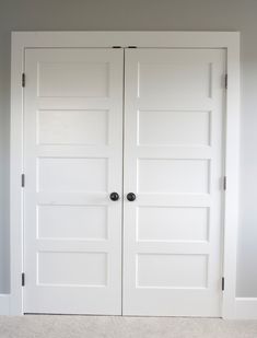 two white doors in a room with carpet