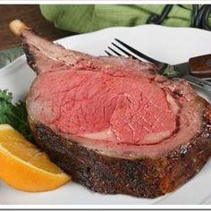 a piece of meat sitting on top of a white plate next to an orange slice