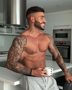 a shirtless man holding a coffee cup in his hand