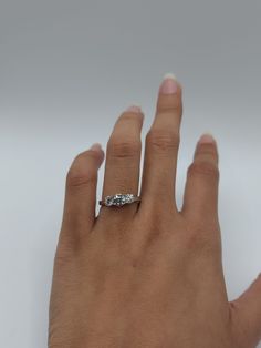 a woman's hand with a diamond ring on top of her left hand, against a white background