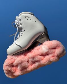 a pair of ice skates on top of a pink fuzzy object in the air