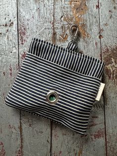 a black and white striped purse with a green button on the front, sitting on a wooden surface