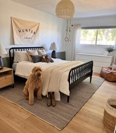 a dog sitting on the floor in front of a bed with white sheets and pillows