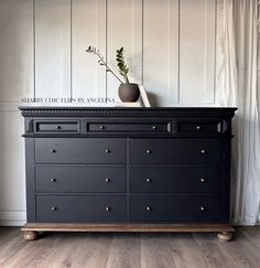 a black dresser with drawers and a vase on top