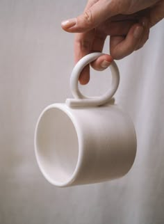 a person holding a white coffee cup with a ring on it